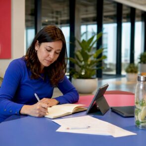 Een vrouw is bezig met het beheren van Azure-kosten op haar tablet, terwijl ze aantekeningen maakt.