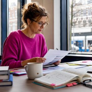 Een vrouw buigt zich over documenten om het digitaliseringsproces binnen de organisatie te onderzoeken.